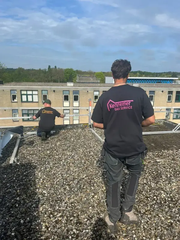 Twee vakmannen van Kennemer Dak Service aan het werk op een plat dak