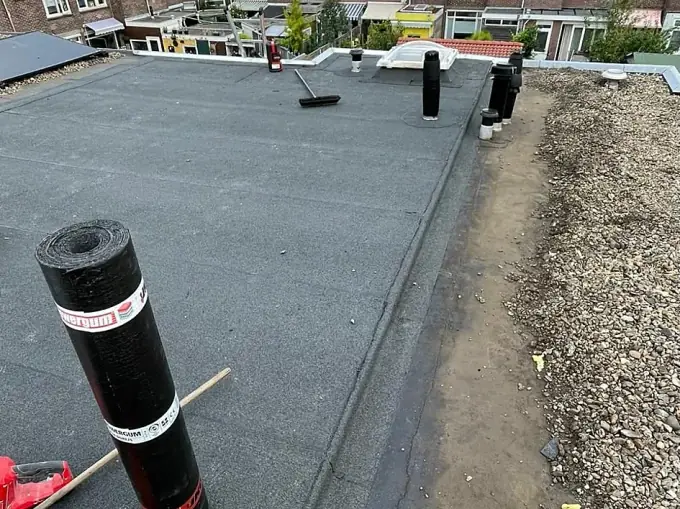 Groot plat dak van een rij woningen met nieuwe bitumen dakbedekking