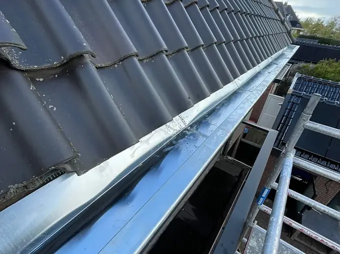 Nieuwe zinken goot langs een pannendak